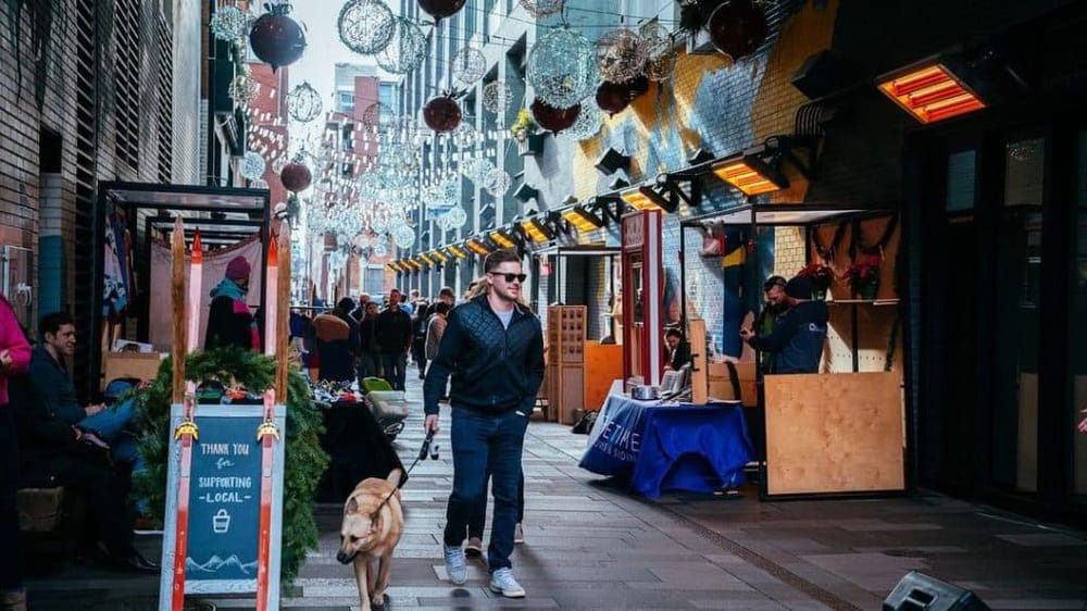 Colorful outdoor market decorated with holiday lights and festive ornaments, bustling with visitors.