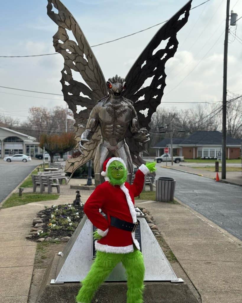 1. Large butterfly statue with a person dressed as the Grinch in a Santa suit in front, holiday street decor.