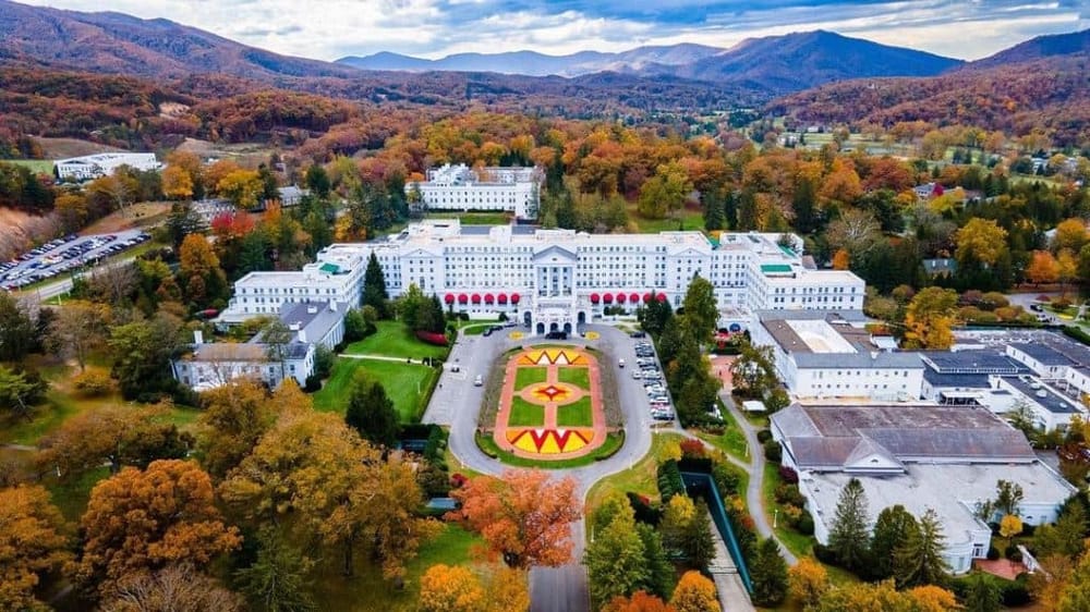 Elegant resort nestled in scenic mountains with lush fall foliage, possibly a luxury hotel or spa.