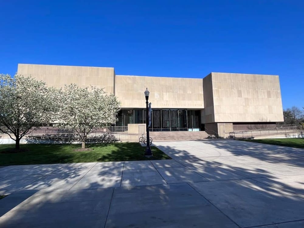 Modern library and theater building with trees under a clear blue sky, optimal for community events and educational programs.