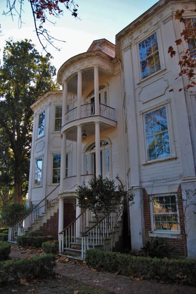 Elegant Victorian-style house with brick stairs, white exterior, and classic architectural details.