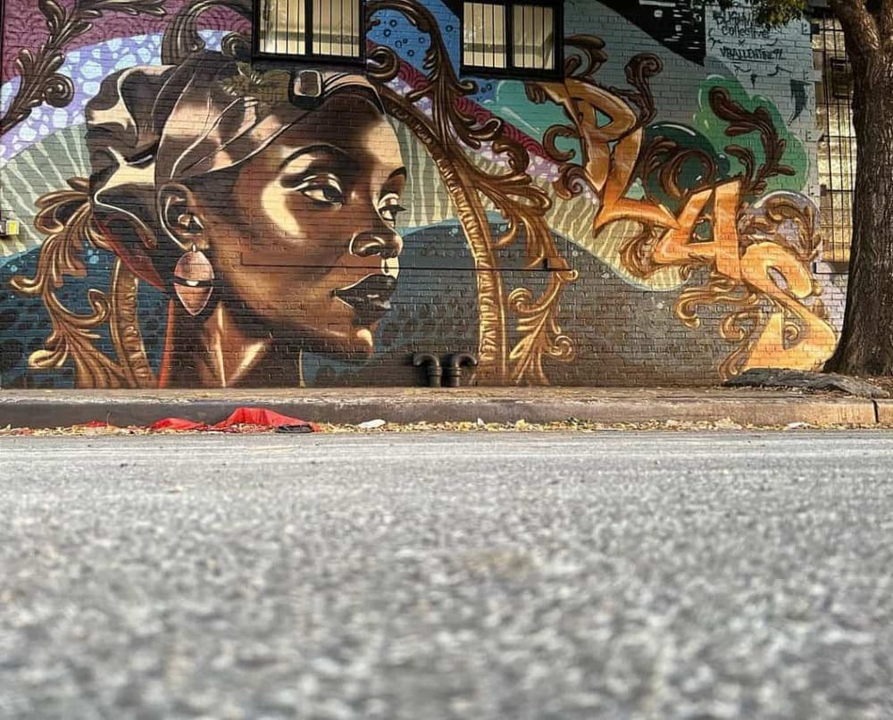 Vibrant street art mural of a woman with detailed hair and jewelry in an urban setting.