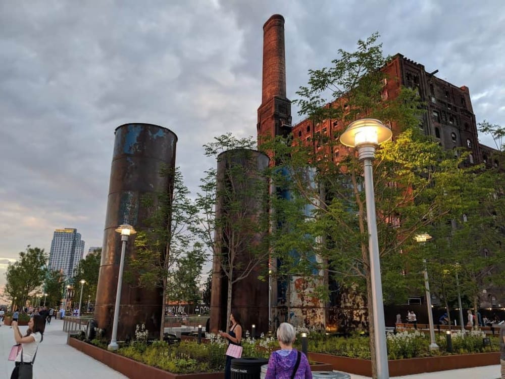 Rustic industrial building with tall smokestacks, modern park features, and city skyline, offering historic charm and urban atmosphere.
