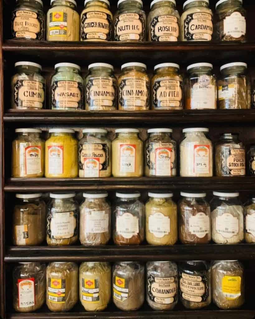 1. Assorted spices in glass jars on wooden shelves at QuestForDirections.