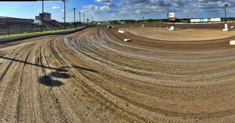 Dirt race track with tire marks under a blue sky, used for off-road dirt track racing.