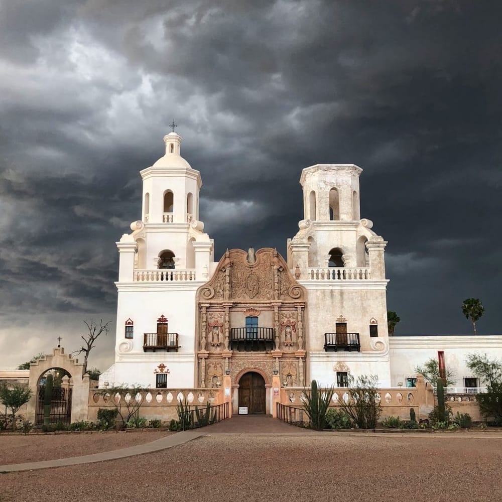 Colorful historic Mexican church with dark stormy sky in background, popular travel destination.