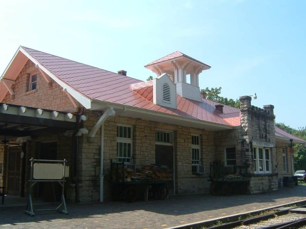 Historic train station with unique architecture and stone details, located in a scenic setting.
