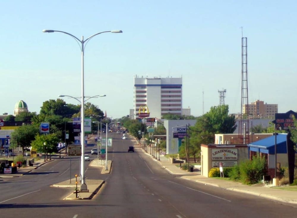 Wide city street view with commercial buildings and streetlights, showcasing urban navigation and local landmarks.