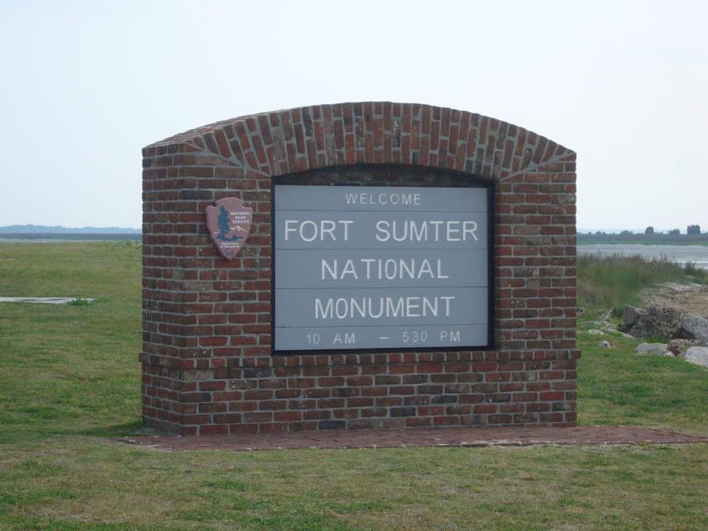 Historic Fort Sumter National Monument entrance sign, open from 10 AM to 5:30 PM, located in Charleston, South Carolina, with scenic water views.