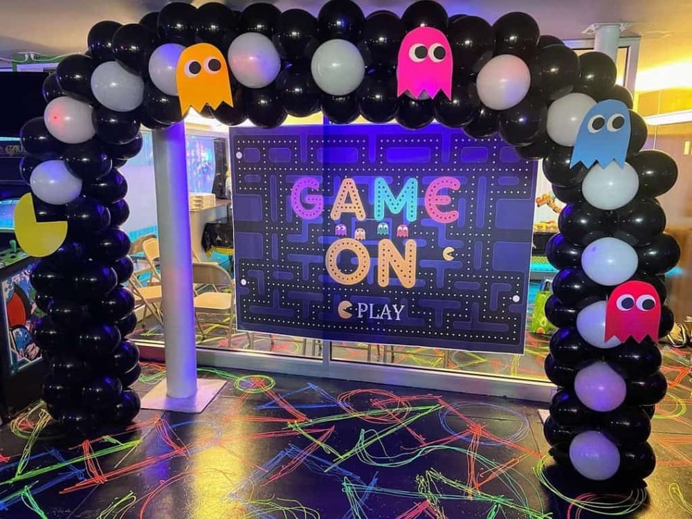 Colorful Pac-Man themed balloon arch at a gaming arcade for kids' entertainment and fun.