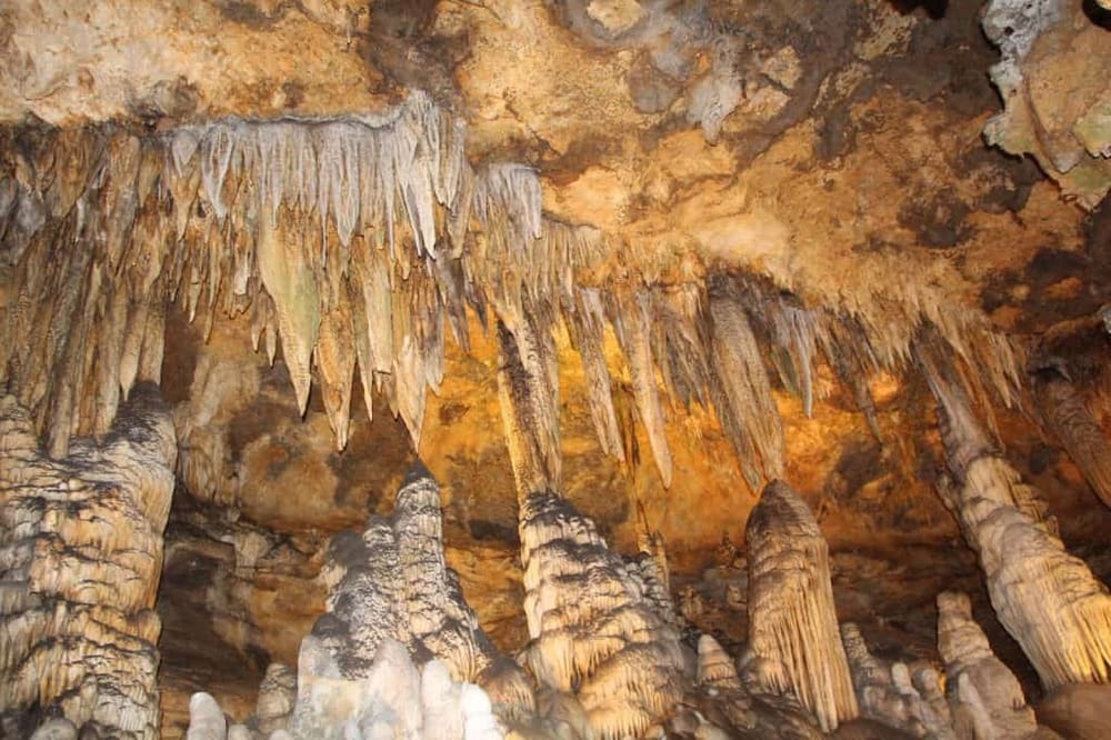Intricate cave formations with stalactites and stalagmites in a scenic underground cavern.