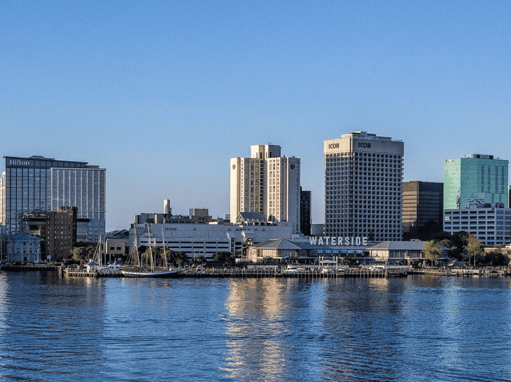 Bright city skyline over water with high-rise buildings and a "WATERSIDE" sign.