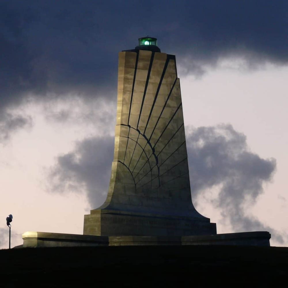 Lighthouse monument at Quest For Directions site with dramatic sky background, serving as a navigation landmark.