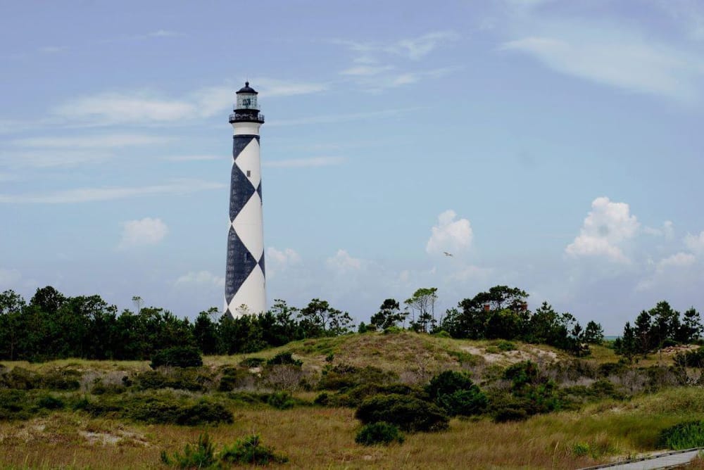 Lighthouse with black and white diamond pattern on the coast of Pensacola, Florida - a popular navigation landmark.