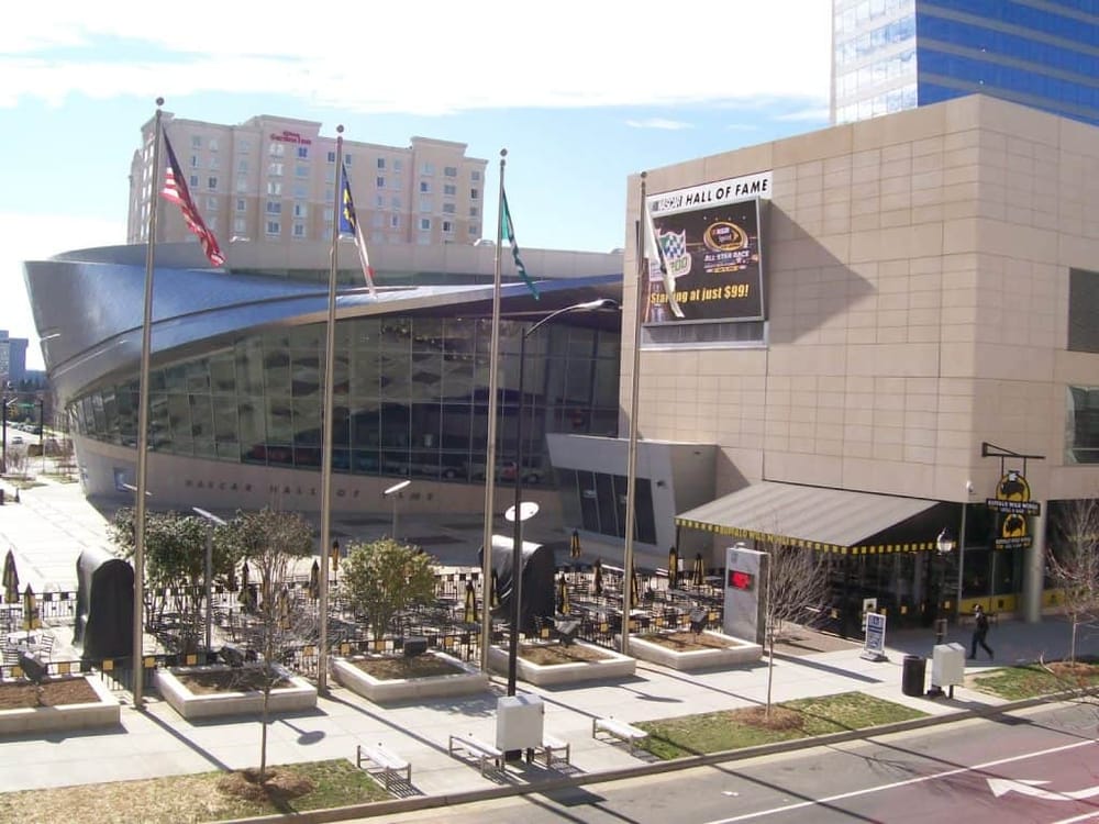 Colorful NASCAR Hall of Fame building with flags, outdoor seating, and digital signage in Las Vegas, Nevada.
