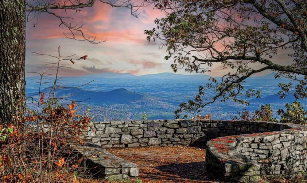 Breathtaking mountain overlook with stone seating and autumn foliage, offering scenic views and outdoor recreation opportunities.