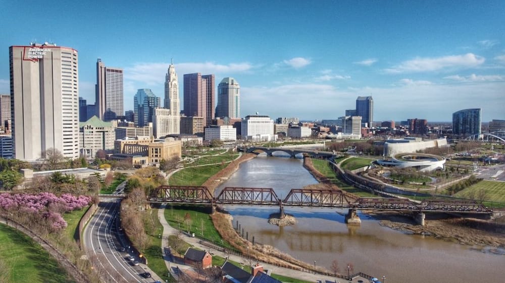 Aerial view of Columbus Ohio skyline with river, parks, and city buildings.