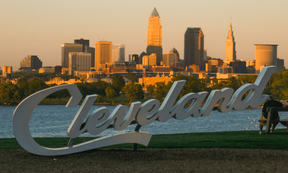 City skyline of Cleveland with iconic Love Cleveland sign by Lake Erie at sunset, showcasing urban beauty and attractions.
