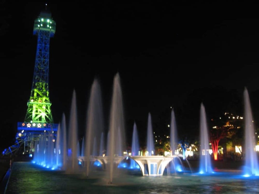 Colorful illuminated tower with water fountain display at night in Quest for Directions.