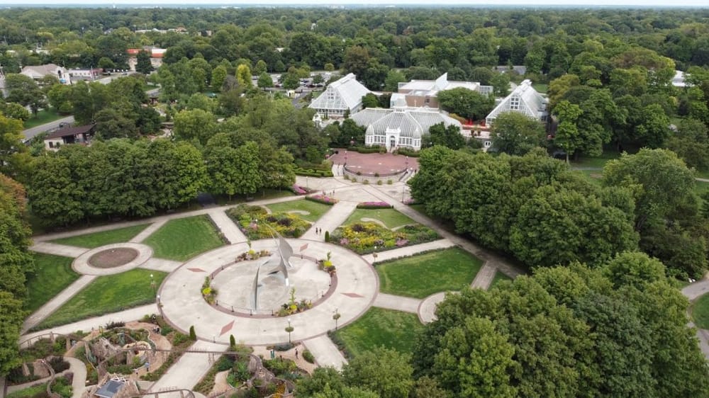 Vineyard Gardens and Glass Greenhouse at Quest for Directions botanical park, surrounded by lush trees.