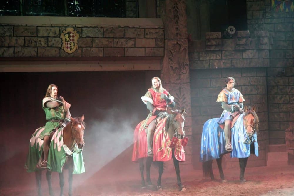 Medieval knights on horseback performing in an indoor arena, highlighting historical jousting reenactment.