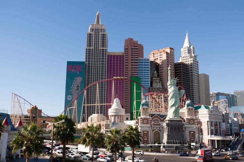 Colorful Las Vegas skyline with replica of Statue of Liberty and roller coaster rides.