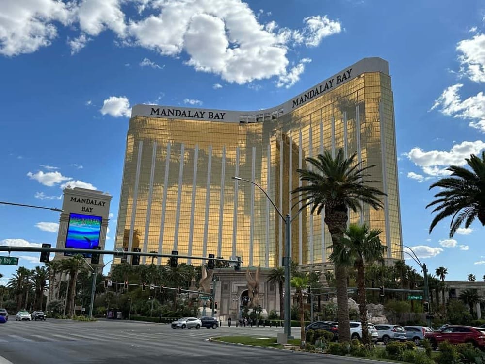 Golden hotel building at Mandalay Bay in Las Vegas with palm trees and blue sky.