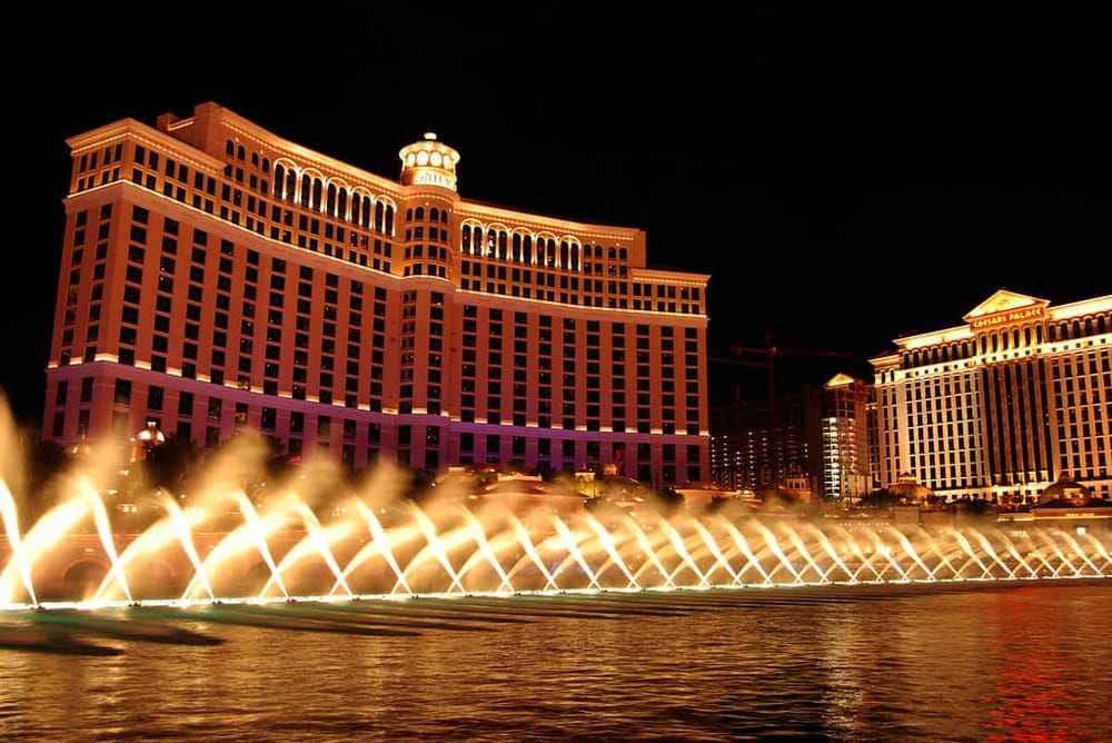 Brightly lit Las Vegas hotel skyline at night with iconic fountains fountain show.