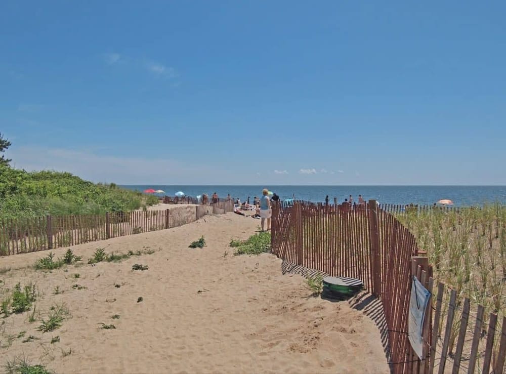 Sunny beach access with sand dunes, wooden fencing, and ocean views at Quest For Directions.