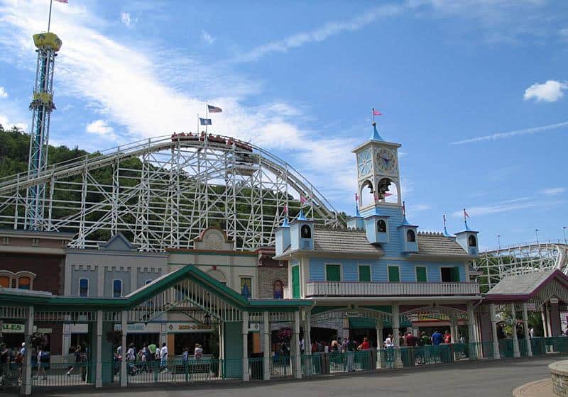 Colorful amusement park entrance with roller coaster in background, family-friendly entertainment venue.