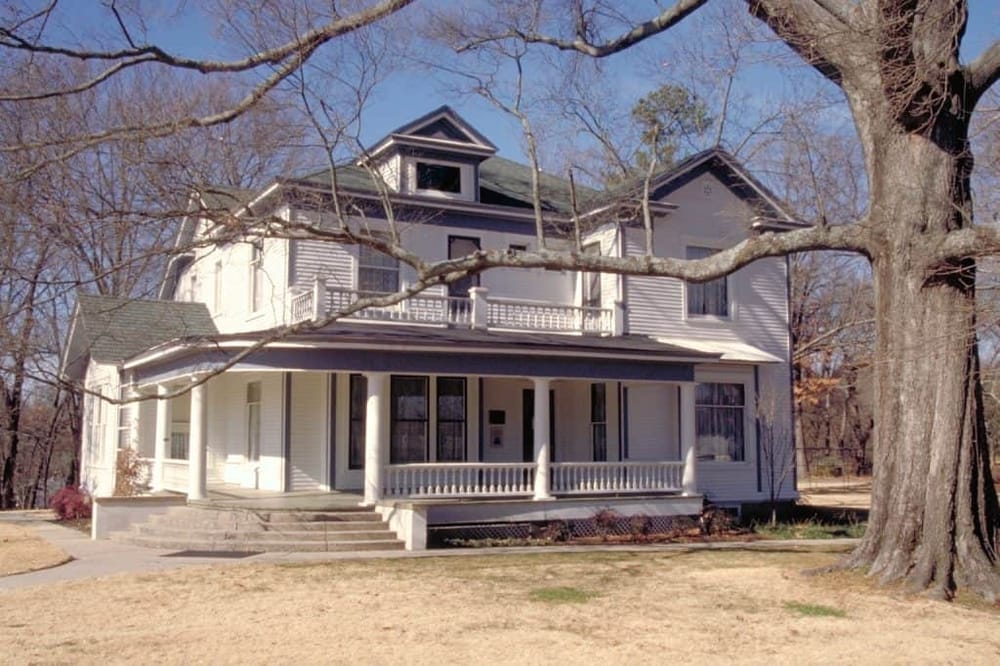 Spacious Victorian-style house with large porch and mature trees, perfect for directions and home search.