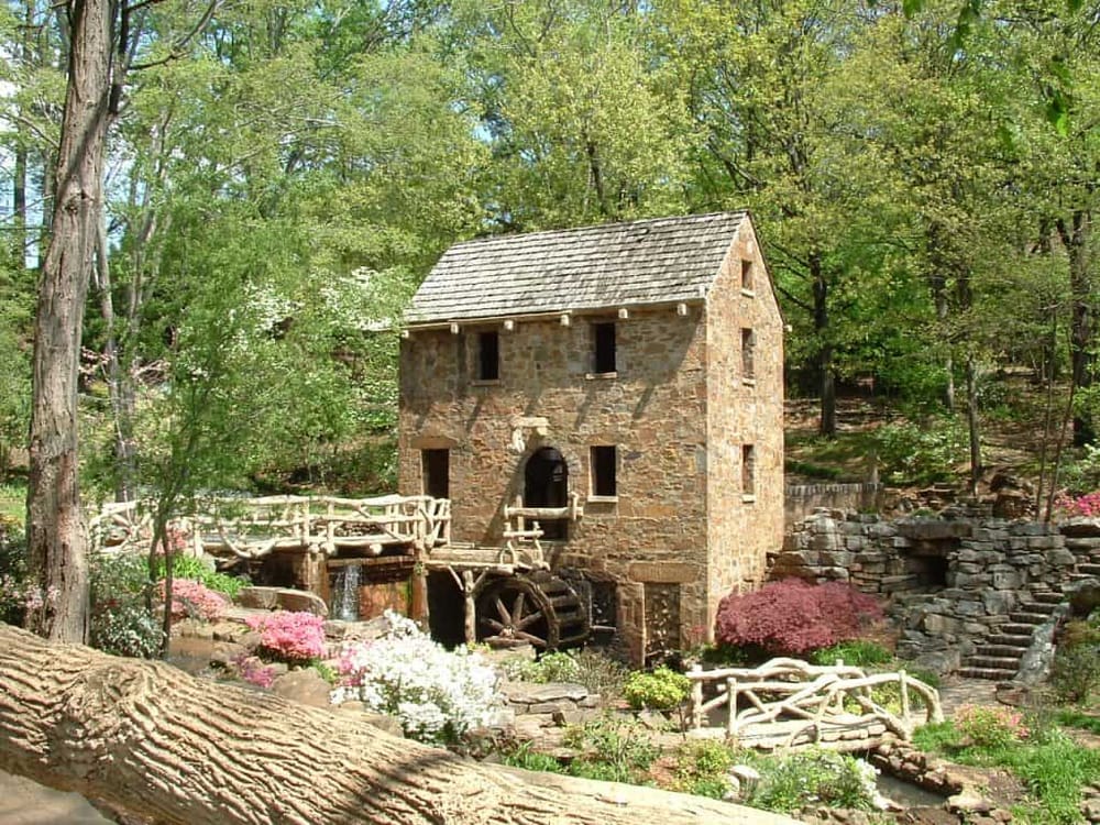 Quaint stone watermill surrounded by lush garden and greenery, inspired by QuestForDirections' scenic locations.