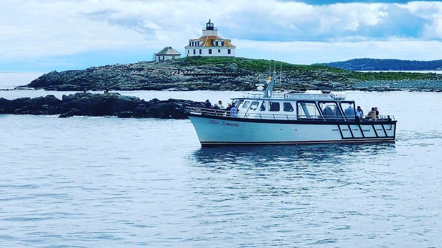 Luxury boat on calm waters near lighthouse, scenic coastal voyage, QuestForDirections travel experience.