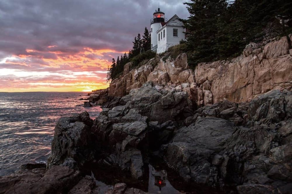 Lighthouse on rocky coast during colorful sunset, scenic ocean view, navigation, travel, maritime lighthouse, scenic lighthouse, coastal scenery.