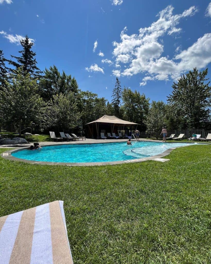 Relaxing outdoor pool surrounded by lush trees and sunny sky at Quest for Directions.