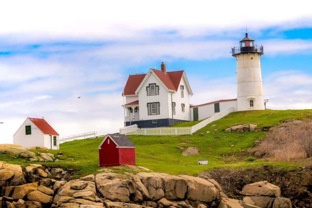 Lighthouse and historic house on rocky shoreline, coastal scenery, New England lighthouse, scenic seaside views.