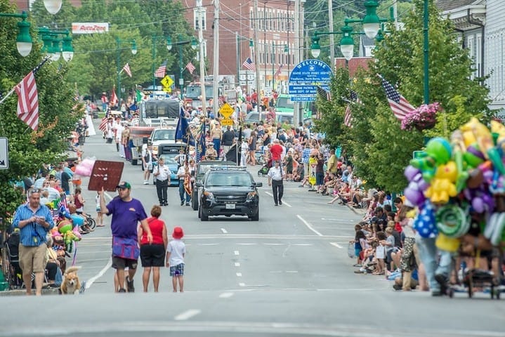 Colorful parade on a lively street with spectators and floats, showcasing community celebration and local culture.