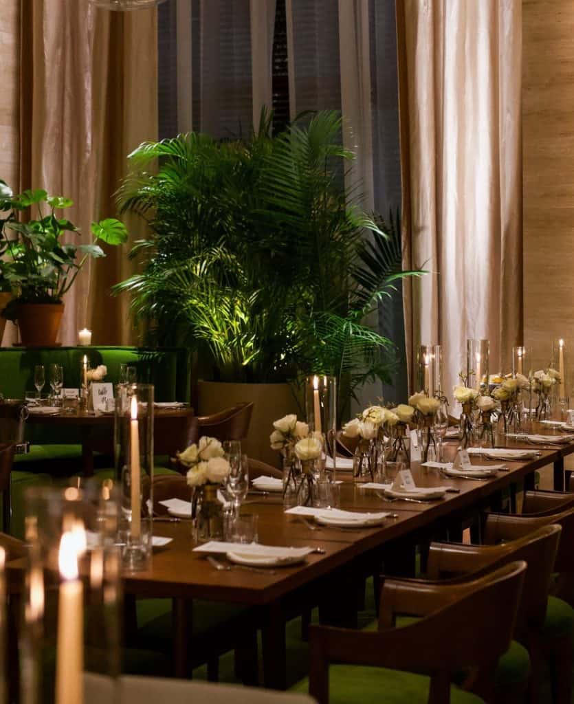 Luxurious restaurant dining setup with elegant decor, lush green plants, and candle-lit tables for special occasions.