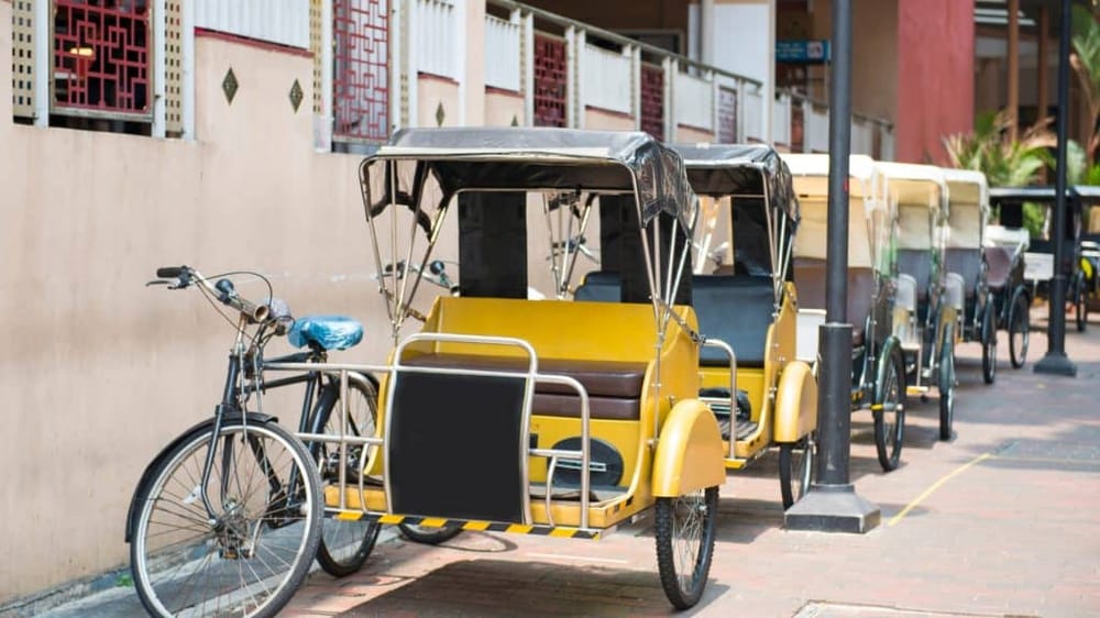 Traditional bicycle rickshaws parked on city sidewalk for transportation services.