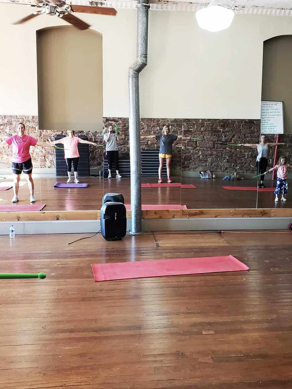 Women participating in a yoga or fitness class with mirrors in a studio setting.