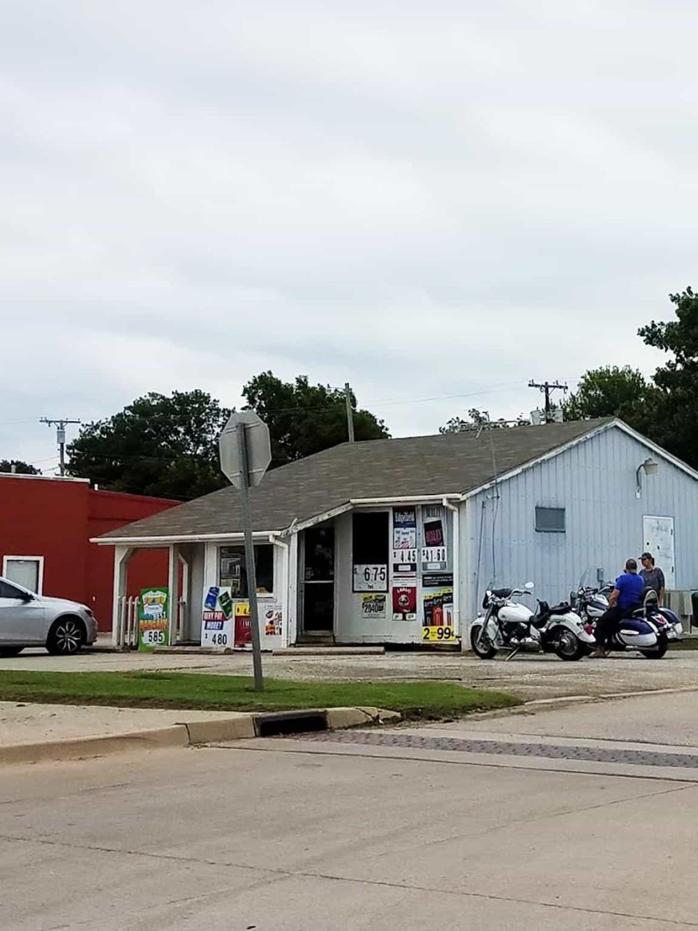 Colorful convenience store with motorcycles parked in front and street signs, highlighting local roadside shopping.