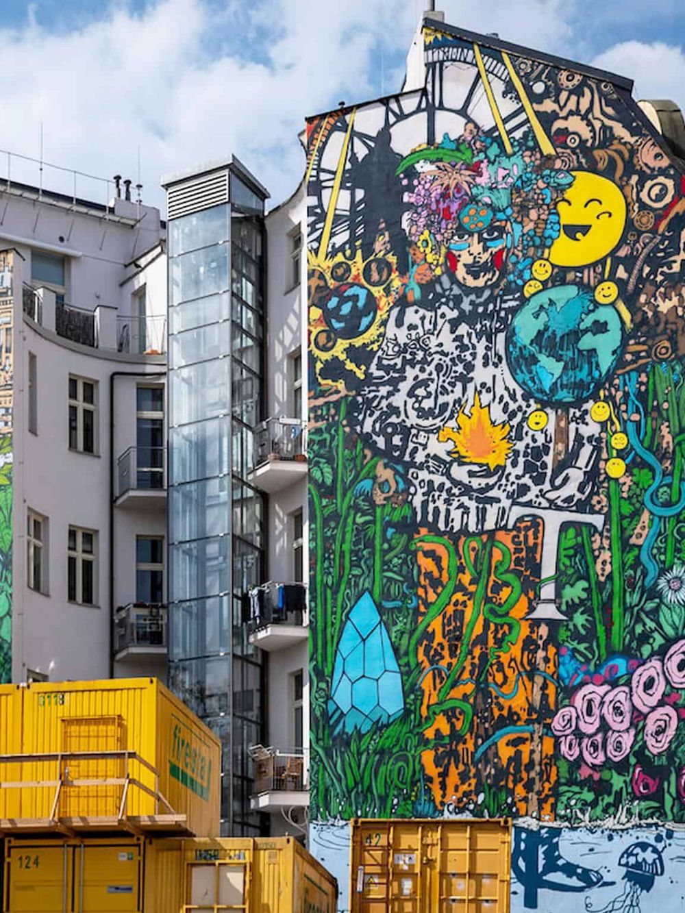 Vibrant urban mural art featuring colorful characters and symbols on building exterior.