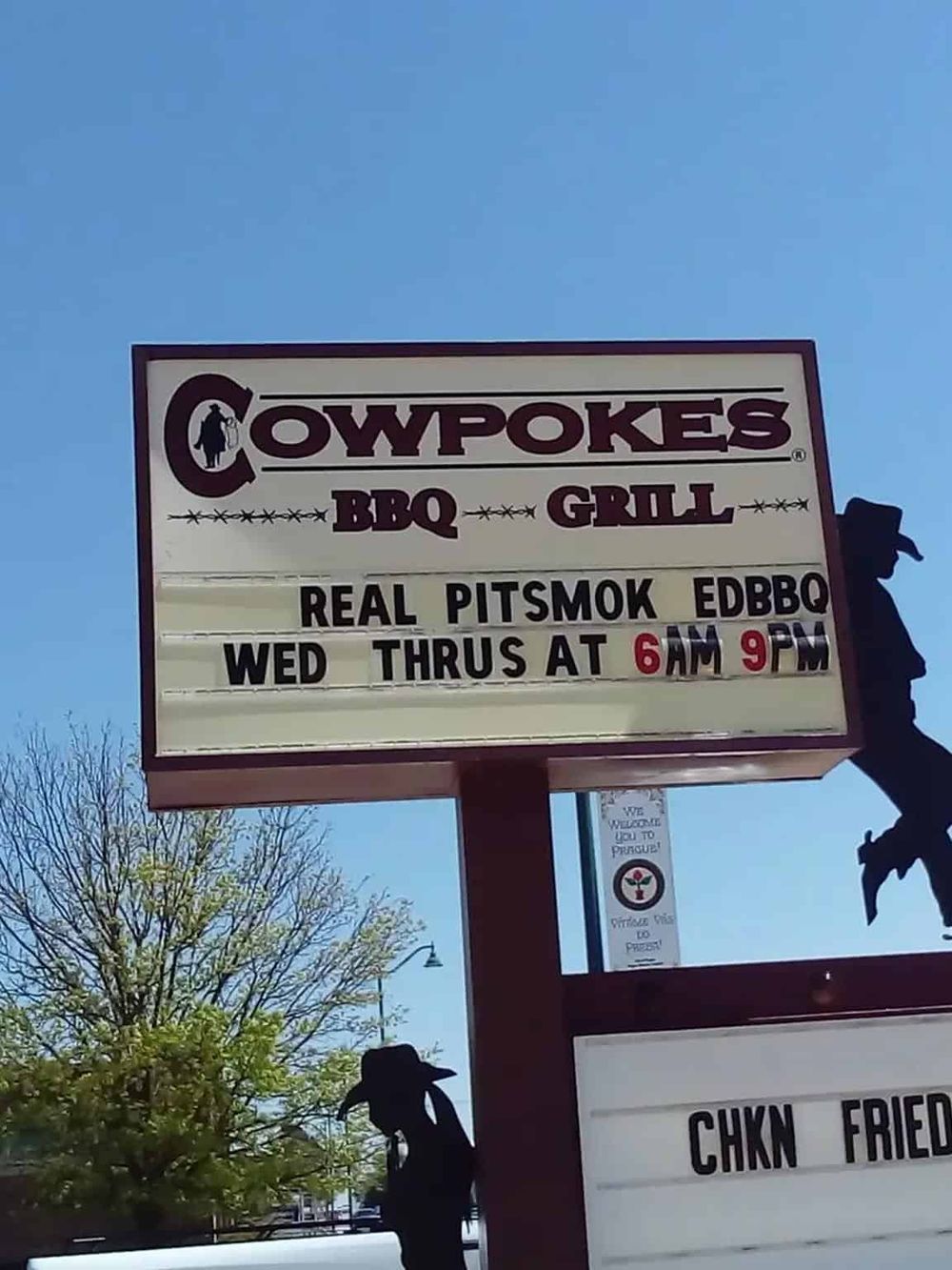 Iconic BBQ restaurant sign for Cowpokes with hours of operation, promoting authentic smoked meats and classic barbecue cuisine.