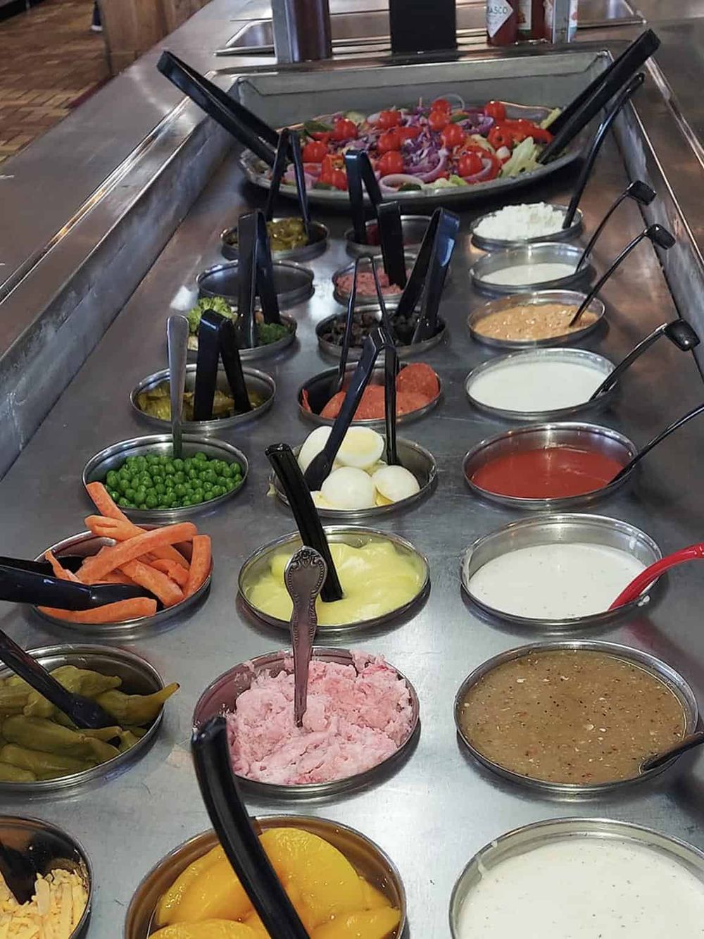 Fresh salad bar with various toppings and dressings at QuestForDirections restaurant.