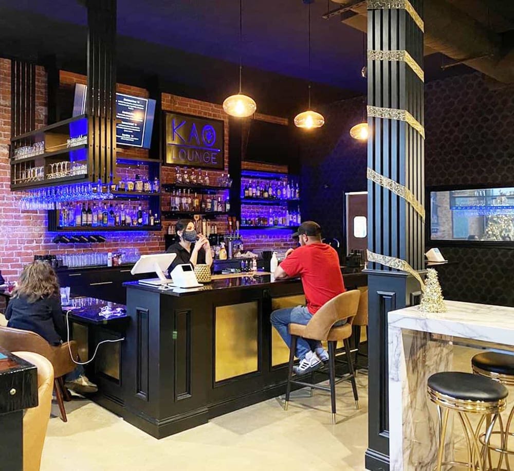 Chic bar at KAÔ Lounge featuring bar seating, modern decor, and an extensive drink menu in an upscale setting.