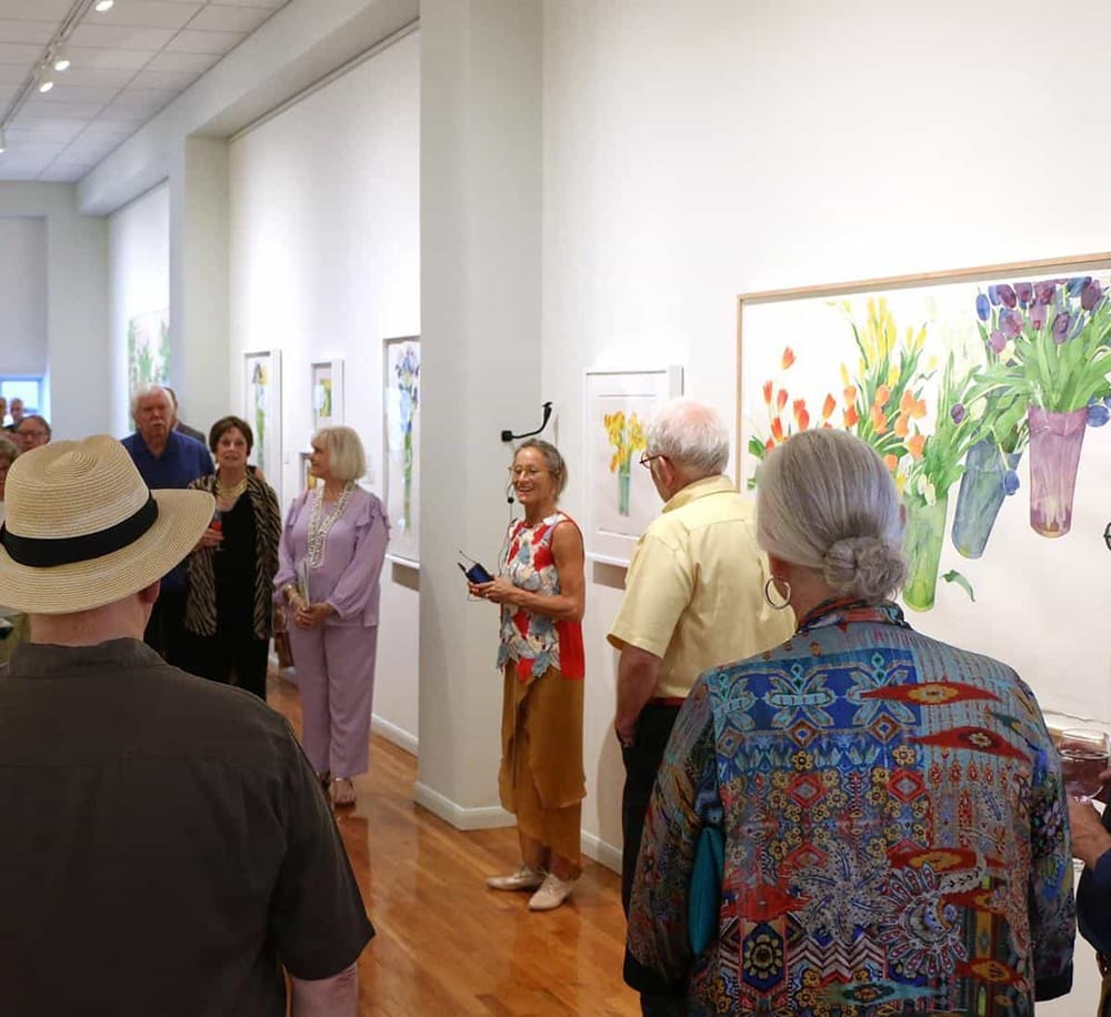 Colorful floral art exhibition at QuestForDirections gallery, enjoyed by a diverse group of art enthusiasts.