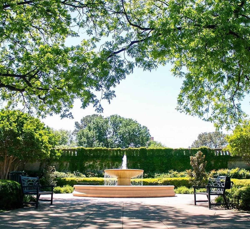 Lush garden with fountain, shaded by trees, perfect for outdoor relaxation and peaceful walks.
