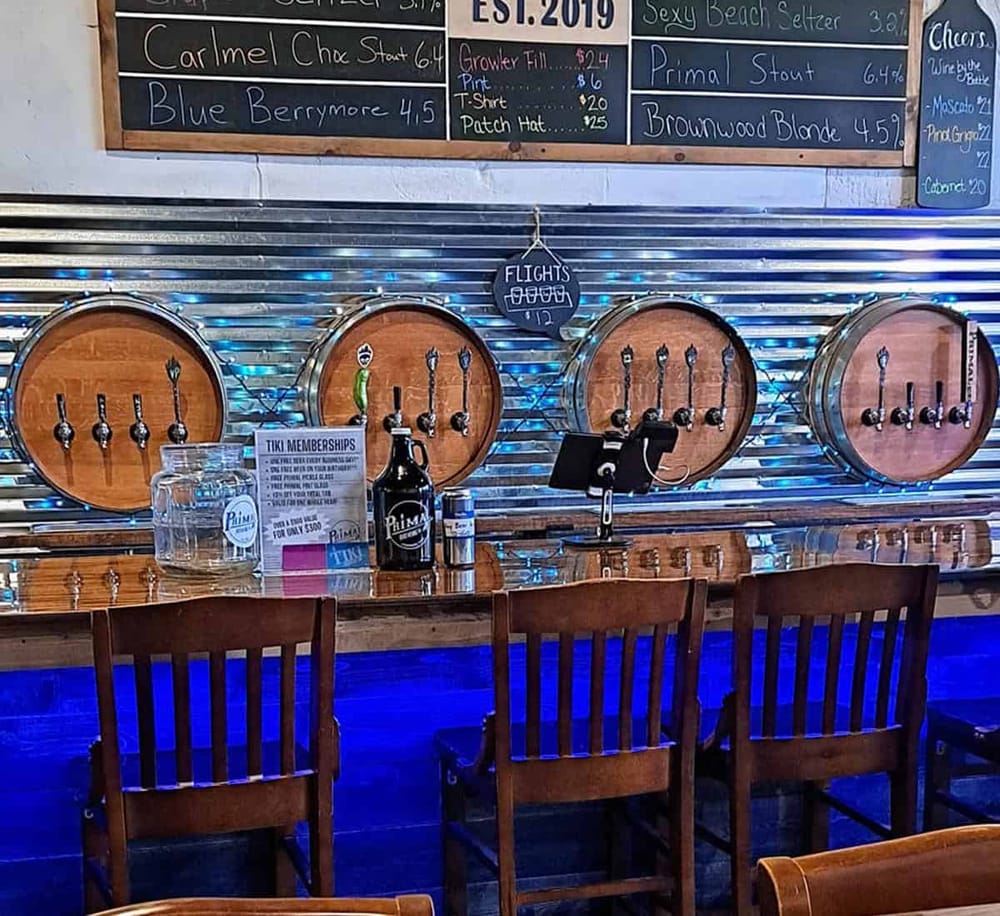 1. Beer taps on a rustic bar with wooden barrels and vibrant blue string lights.
