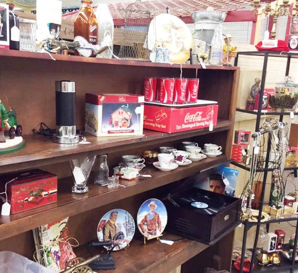 Vintage kitchenware, Coca-Cola collectibles, and decorative figurines at a thrift store.