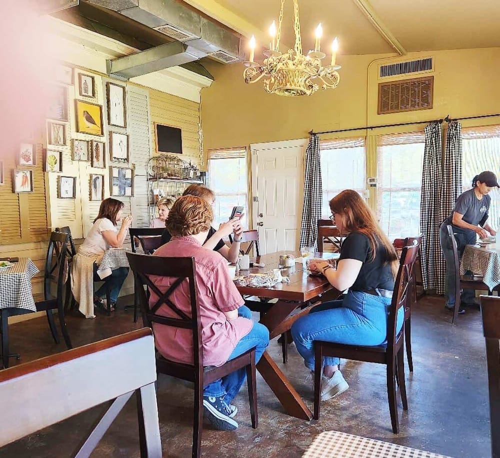 Cozy restaurant interior with guests dining and a vintage chandelier, showcasing inviting atmosphere for local dining.